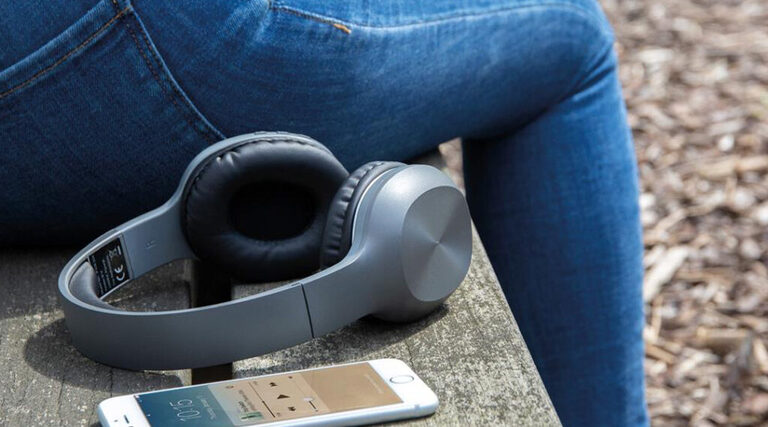 cuffie bluetooth appoggiate su panchina con smartphone che riproduce musica