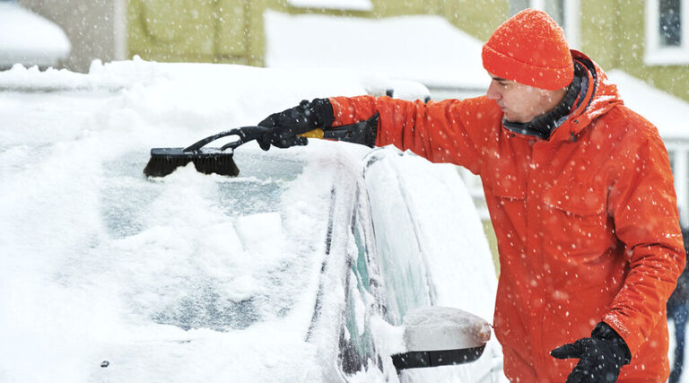 uomo che utilizza raschietto per il ghiaccio per pulire auto