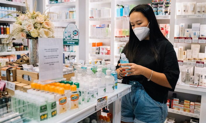 donna con mascherina in farmacia che riceve gadget aziendali