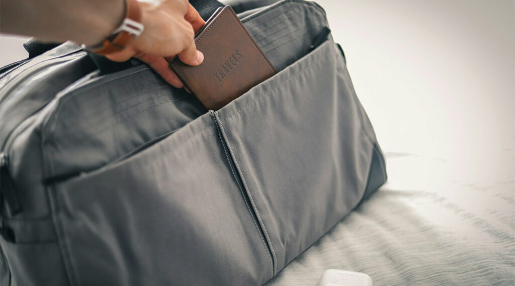uomo che mette il passaporto dentro il suo borsone da viaggio
