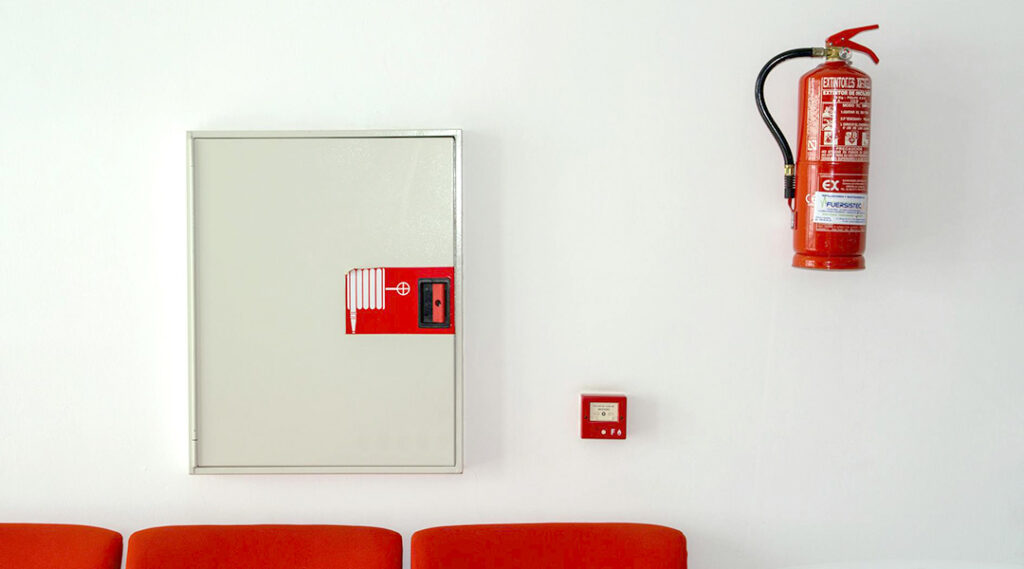 Dispositivi di sicurezza antincendio in azienda per una maggiore sicurezza sul lavoro: estintore e pulsante di allarme visibili e accessibili