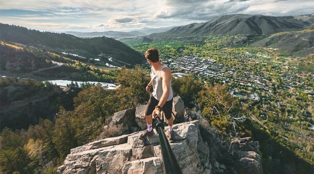 ragazzo con GoPro che fa un video con un paesaggio naturale