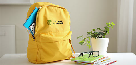 zaino giallo personalizzato con il logo della scuola su una scrivania bianca