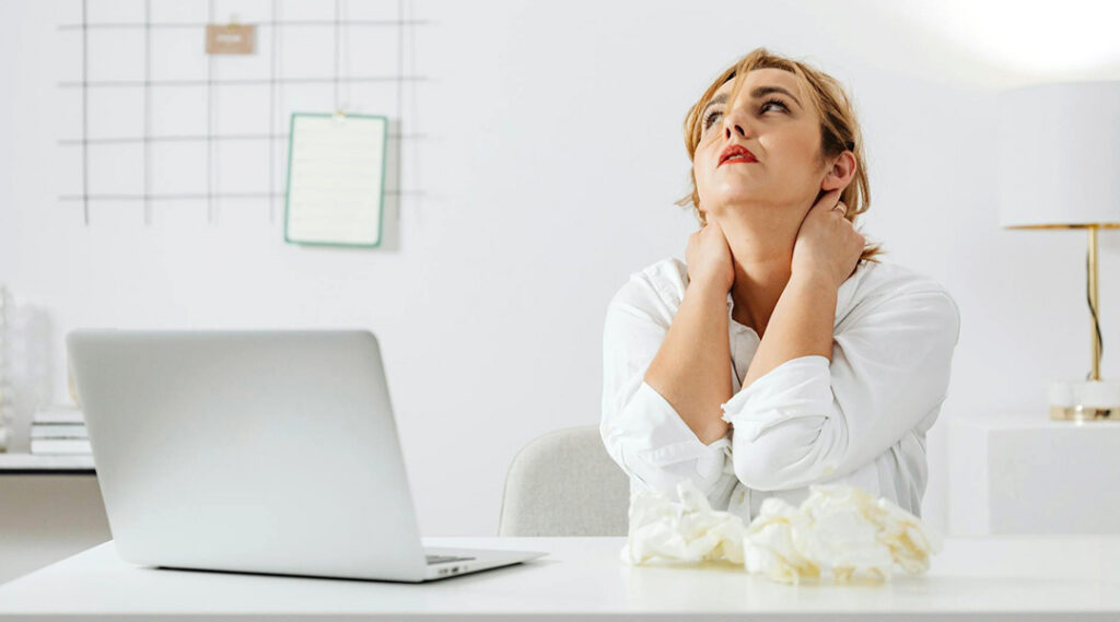 Donna alla scrivania con dolore alla schiena durante il lavoro