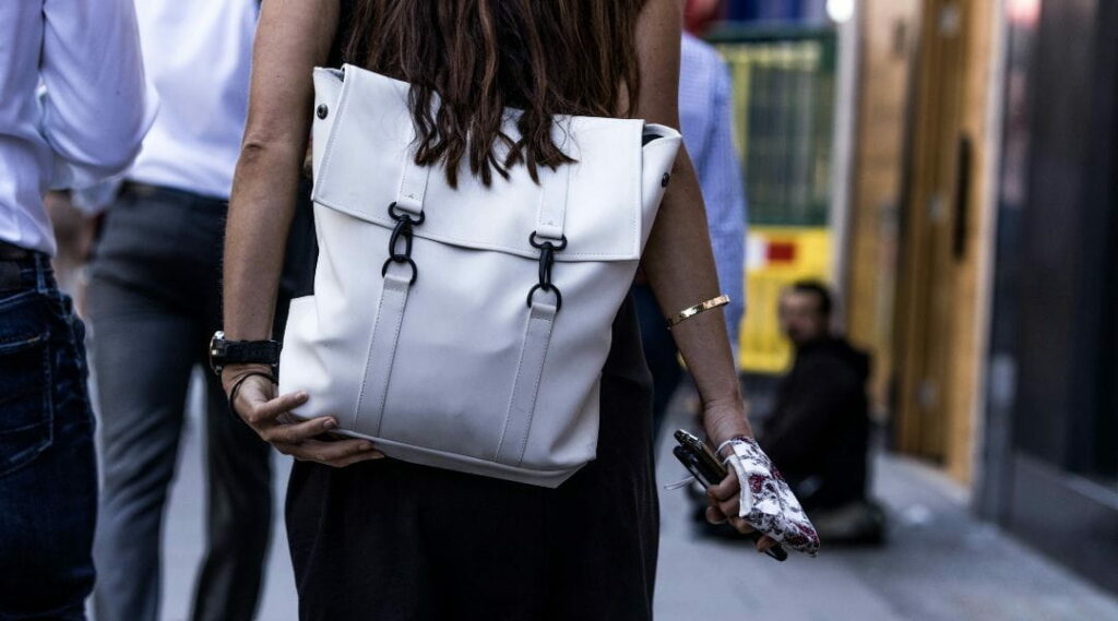 Donna di spalle con zaino bianco in contesto urbano