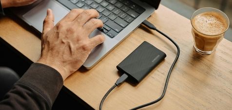 Laptop collegato a una power bank su un tavolo con caffè