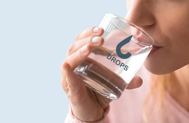 Donna che beve acqua da un bicchiere di vetro personalizzato